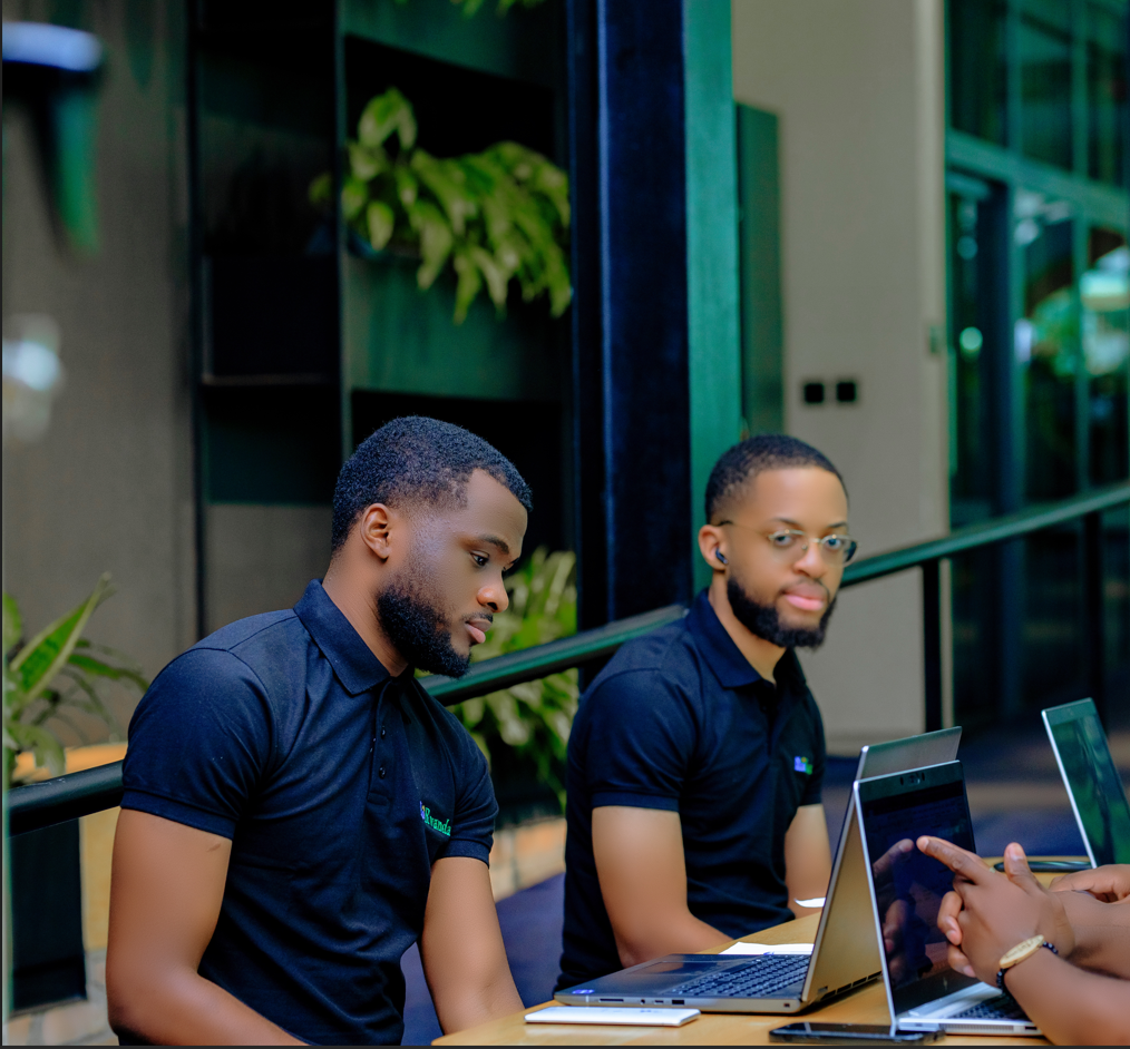 Two IkoRwanda developers collaborating on laptops at an outdoor workspace