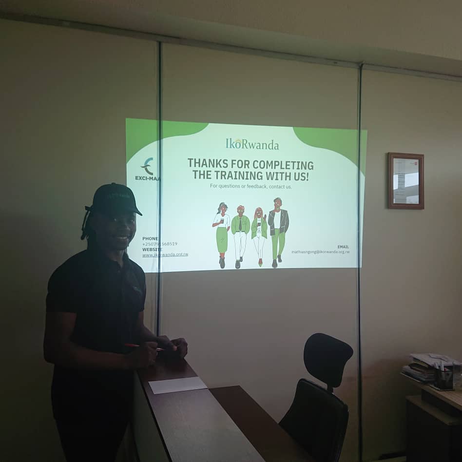 Mathias standing beside IkoRwanda training completion slide at Exci-Maa